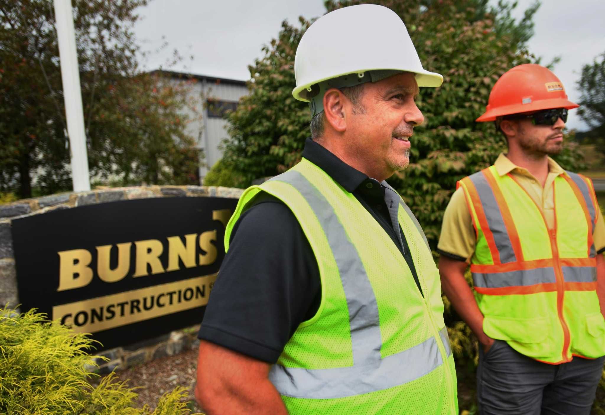 Burns Construction employees standing beside a Burns Construction sign