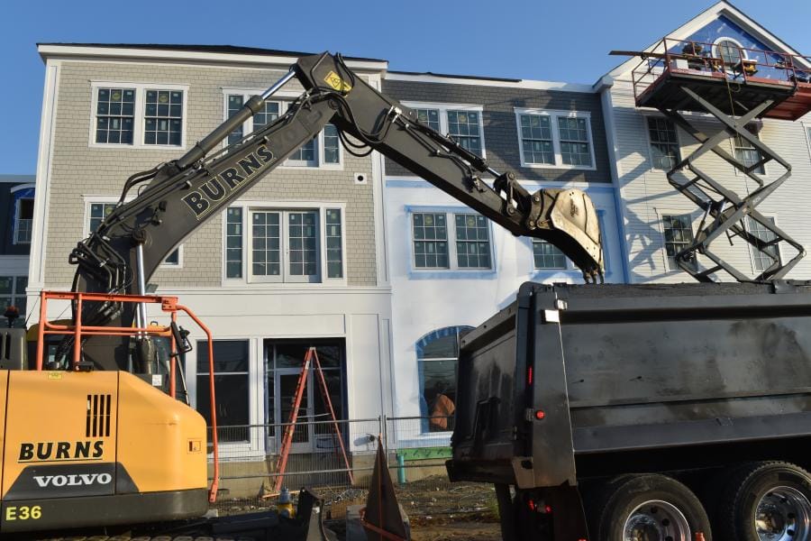 Burns Construction branded excavator at a multi-story commercial building site
