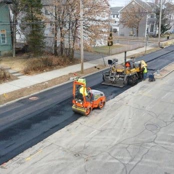 Aerial view of a road roller compacting fresh asphalt on a residential street